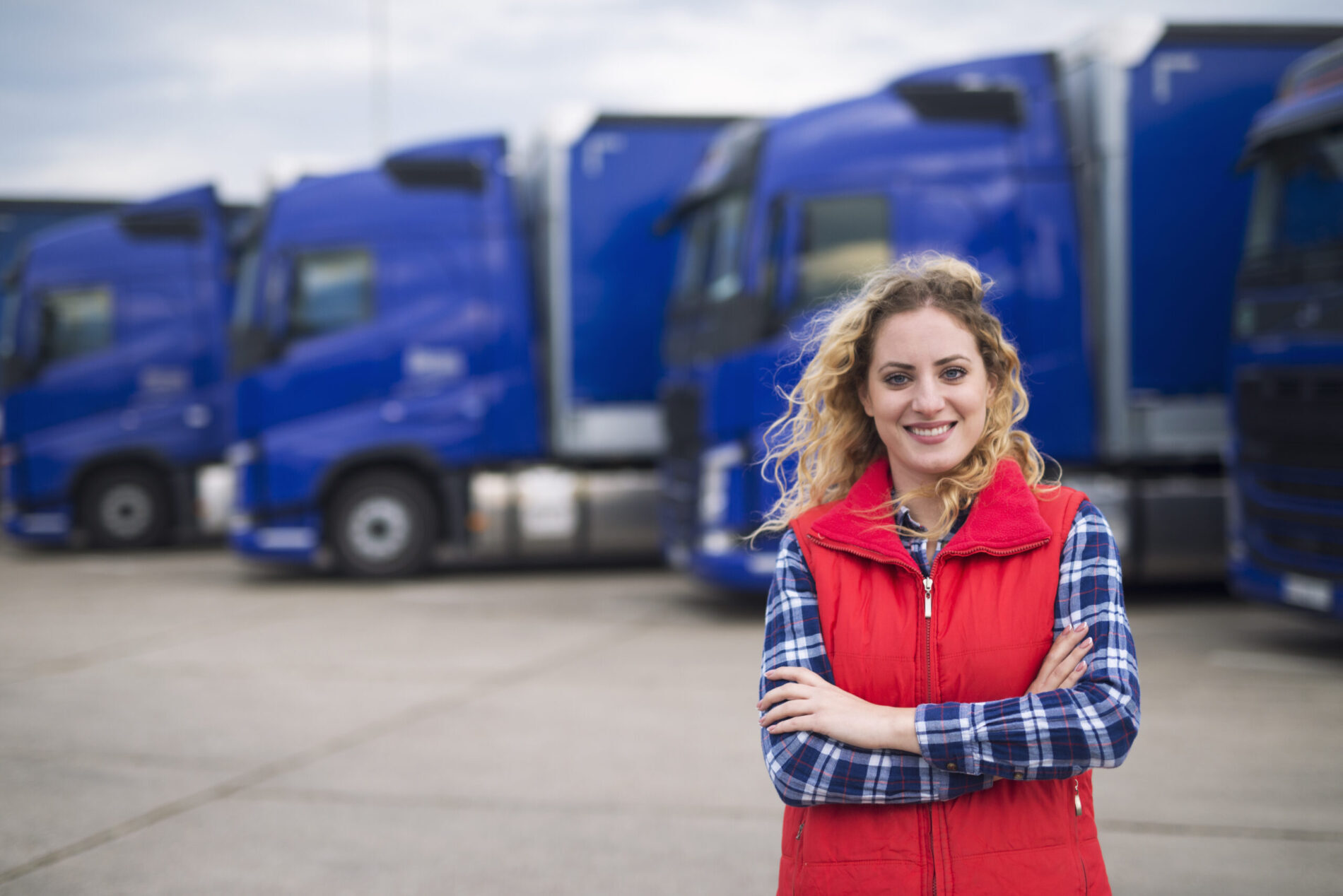 Portrait of Manitoba woman truck driver in casual clothes standing in front of Transportation truck.