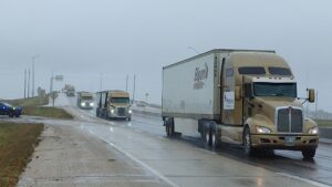 Four yellow trucks on a wet road