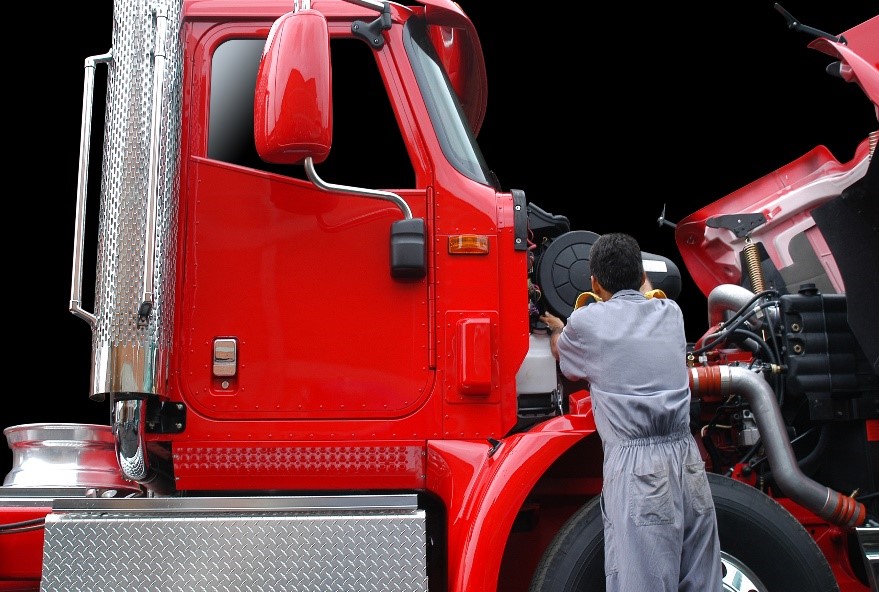 car mechanic checking on the engine of a red truck