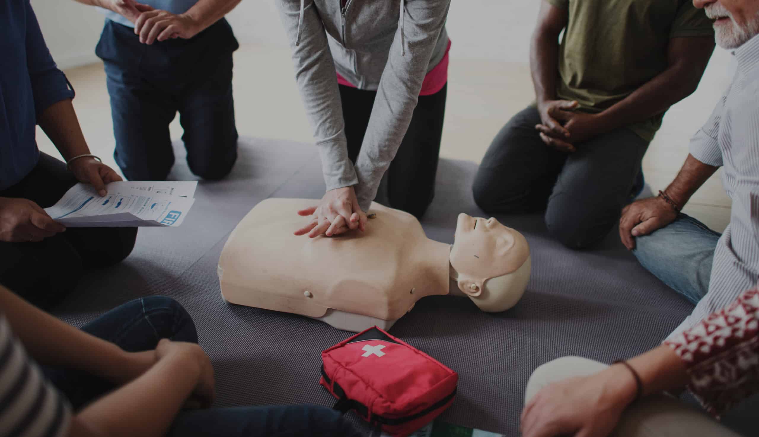 Instructor demonstrating CPR on mannequin at first aid training