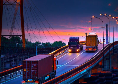 Commerical trucks on a bridge at twilight.
