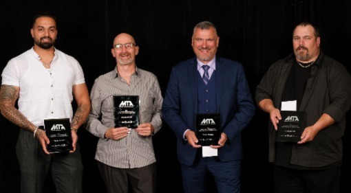 A group of four people holding plaques for winning a top team award.