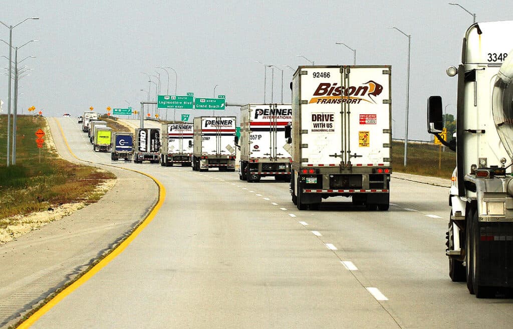A picture of a line of trucks on on overpass.
