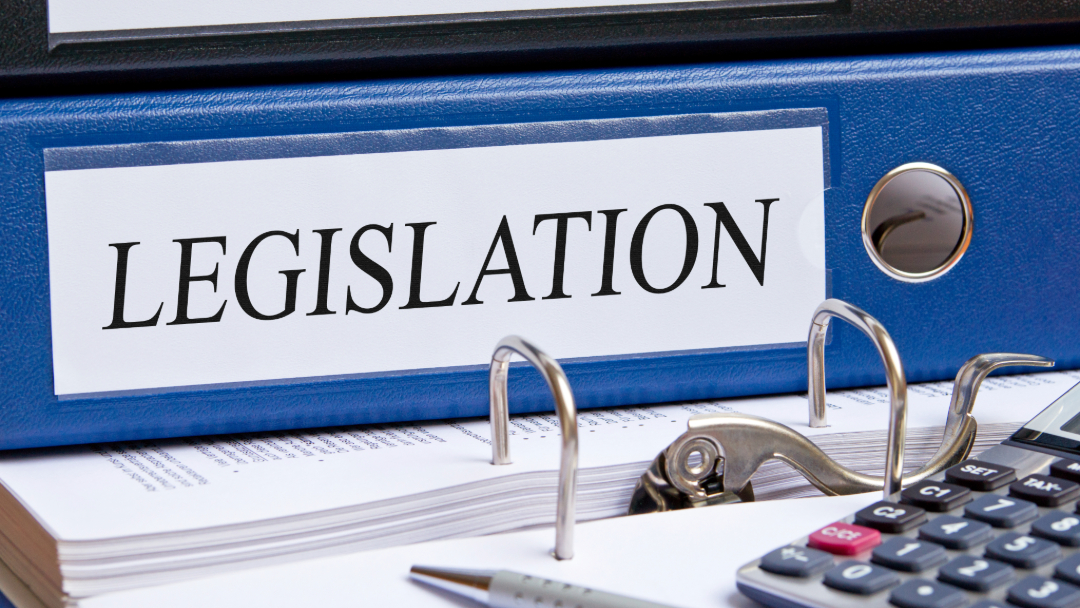 An office desk with a blue binder labelled Legislation on its spine.
