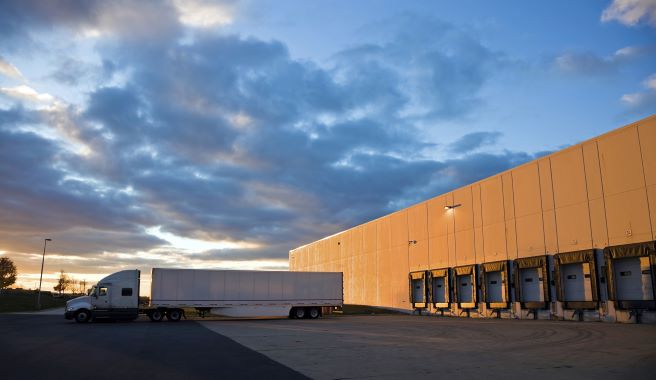 A truck backing up to warehouse doors