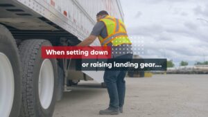 A picture of a person standing beside a trailer preparing to crank the dolly legs.