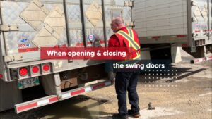 A picture of a person at the back of a trailer preparing to open the swing doors.